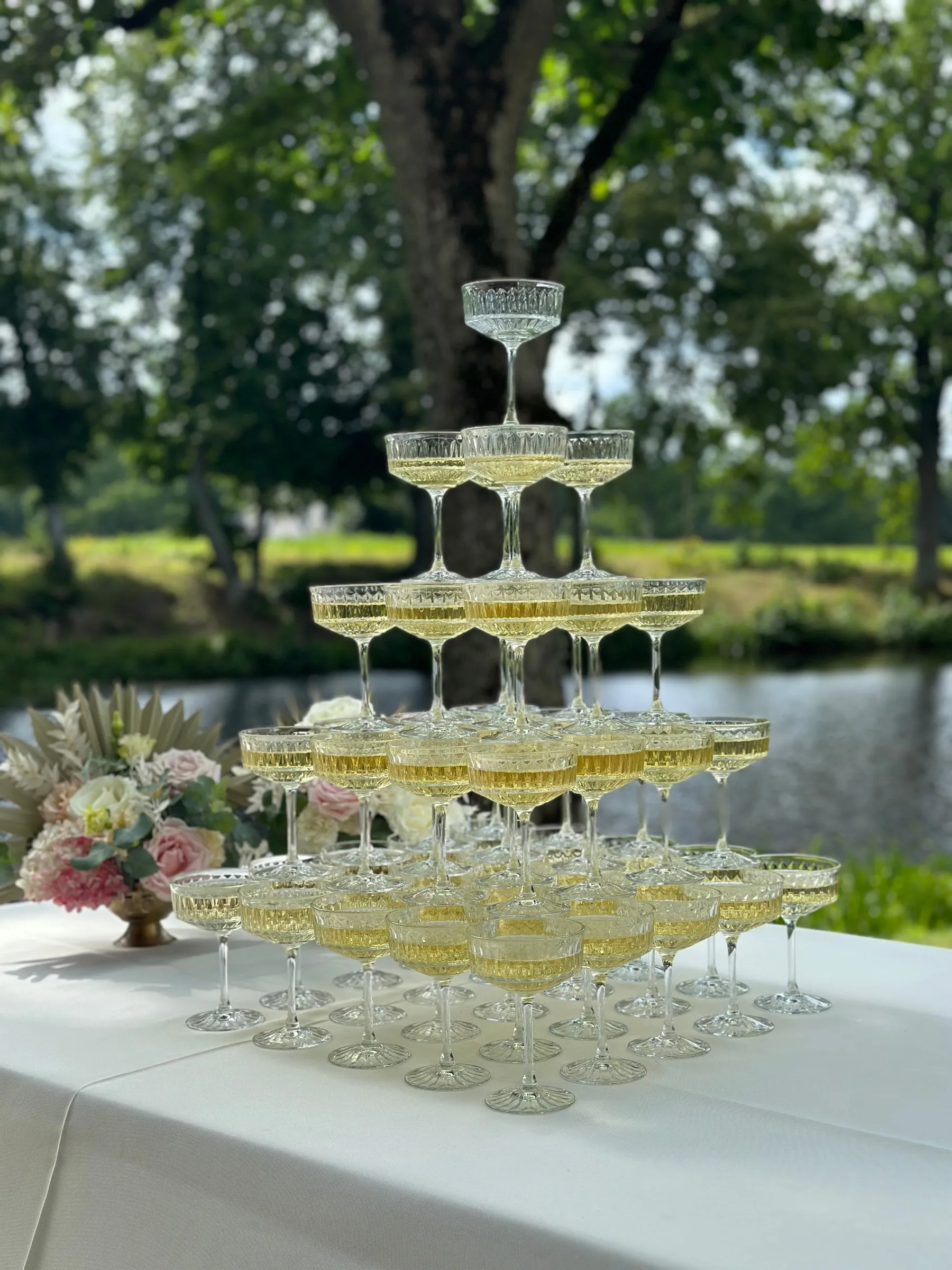 Šampanieša glāžu piramīda pie dīķa pils parkā